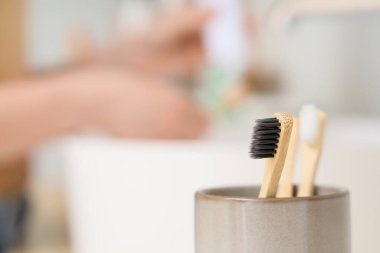 Banyoda lavabonun yanındaki fırçaya diş macunu süren genç bir kadın.