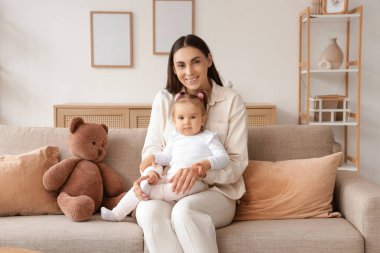 Anne ve bebeği evdeki kanepede oturuyor.