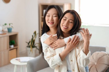Güzel, mutlu Asyalı kız kardeşler evde sarılıyor.