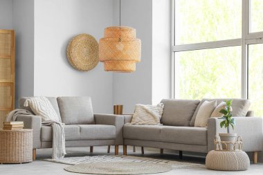 Oturma odasının içinde kanepeler ve büyük pencereler var.