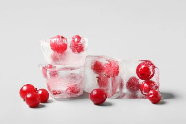 Gri zemin üzerinde buz küpleri içinde donmuş kızılcıklar