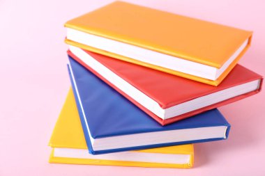 Pembe arkaplan üzerine renkli kitap yığını, yakın plan