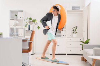 Dizüstü bilgisayarı ve yüzme ringinde sörf yapan genç bir iş adamı. Yaz tatili