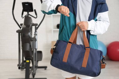 Spor çantalı genç adam spor salonunda akıllı adam kontrol ediyor.