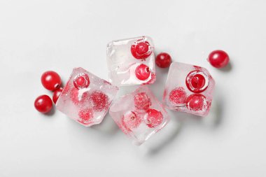 Gri zemin üzerinde buz küpleri içinde donmuş kızılcıklar