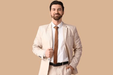 Bej arka planda şık takım elbiseli yakışıklı bir iş adamı.
