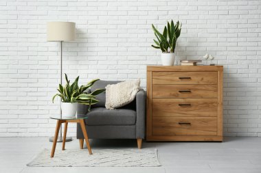 Beyaz tuğla duvarın yanındaki koltuklu, çekmeceli ve sansürlü oda.