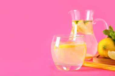 Bir bardak taze limonata ve pembe arka planda nane şekeri.