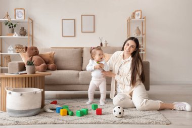 Anne ve bebeği evde oyuncaklarla oynuyorlar.