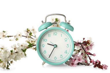 Beyaz arkaplanda çiçek açan bahar dalları ve alarm saati