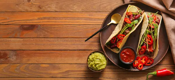 Ahşap zemin üzerinde taze taco bulunan peçete ve tepsi.