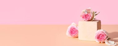 Şık yüzüklü dekoratif podyum ve renkli arka planda güzel güller.