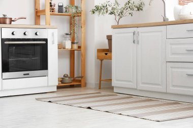 Beyaz tezgahlı ve çizgili halılı aydınlık mutfağın içi.