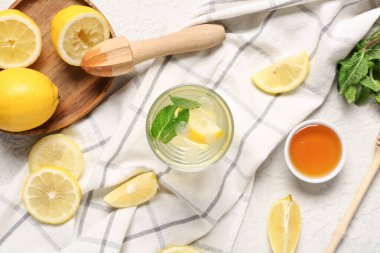 Bir bardak taze limonata ve beyaz arka planda bir kase tatlı bal.