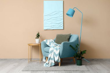 Interior of living room with grey armchair, table and lamp