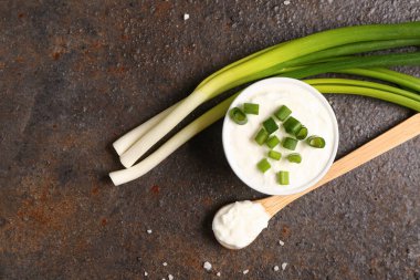 Koyu arkaplanda dilimlenmiş yeşil soğanla bir kase lezzetli ekşi krema.