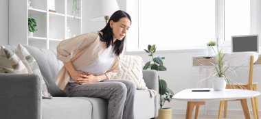 Evde şiddetli karın ağrısı çeken genç bir kadın var.