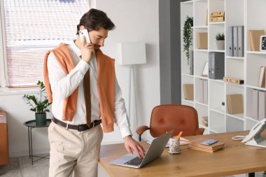 Ofiste cep telefonuyla çalışan yakışıklı iş adamı.