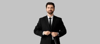 Siyah ceketi açık arkaplanda ilikleyen yakışıklı adam.