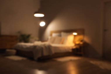 Karanlık odanın bulanık manzarası, yatak ve parlayan lambalar.