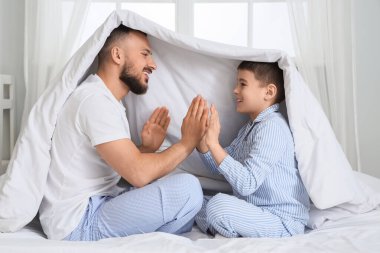 Pijamalı mutlu bir baba. Oğluyla evde el çırpıyor.