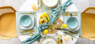 Lokantada güzel lale çiçekleri, mumlar ve altın çatal bıçak seti olan şık bir masa.