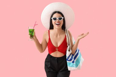 Pembe arka planda kokteyl ve plaj aksesuarları olan mutlu bir iş kadını. Tatil kavramı