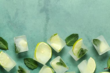Buz küplerinde donmuş kireç dilimleri ve yeşil arka planda nane yaprakları.