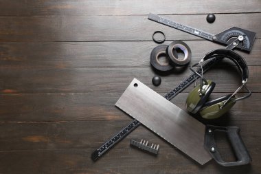 Ahşap arka planda farklı inşaat araçları ve koruyucu kulaklık