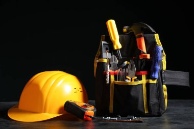 İnşaat araçlarına sahip çanta ve siyah arka planda kalın başlık