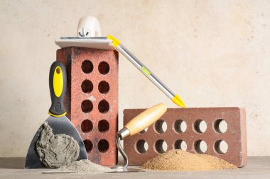 Gri grunge arka planına karşı masadaki tuğlalar, kum ve inşaat araçları