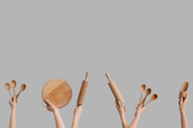 Gri arka planda ahşap mutfak aletleri olan kadın elleri.