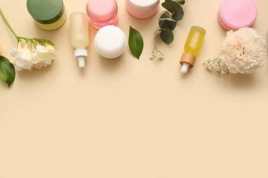Bej arka planda farklı kozmetik ürünleri ve güzel çiçekler