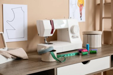 Atölyedeki terzi masasında bant ölçüsü ve iplik makarasıyla kutu, yakın plan.