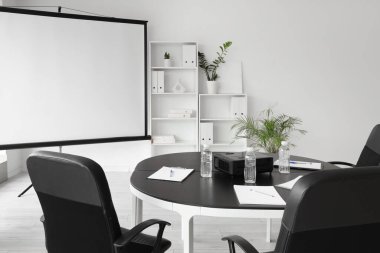 Boş projektör ekranı ve masası olan konferans salonunun içi