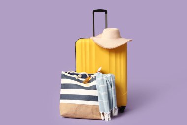 Leylak arka planında plaj aksesuarları olan bavul