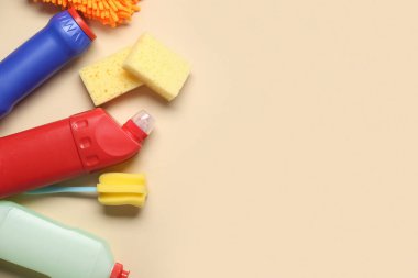 Renkli arka planda deterjan şişeleri ve farklı temizlik malzemeleriyle kompozisyon