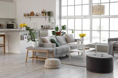 Mutfağın içinde tezgahlar, kanepe ve vazolarda nergisler var.