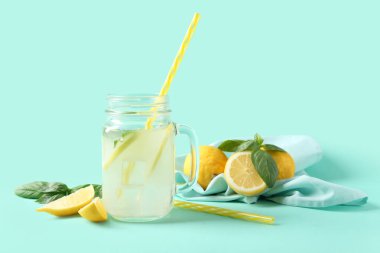 Turkuaz arka planda nane ve fesleğen yapraklı bir kavanoz taze limonata.