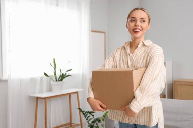 Evde paket kutusu olan genç bir kadın.