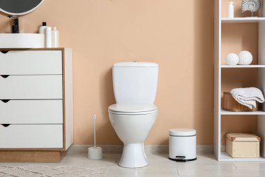 İçinde klozet, lavabo ve çöp olan şık bir tuvalet.