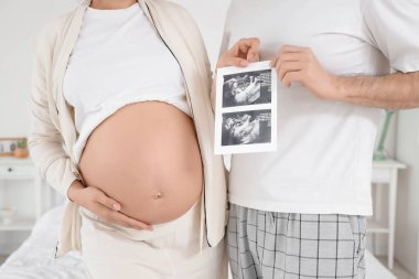Yatak odasında ultrason görüntüsü olan mutlu hamile çift.