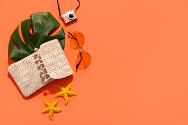 Kırmızı arka planda deniz yıldızları, yeşil yaprak ve plaj aksesuarları ile yaz kompozisyonu