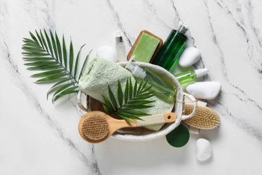 Beyaz arka planda farklı spa malzemeleri ve palmiye yaprakları olan hasır sepet.