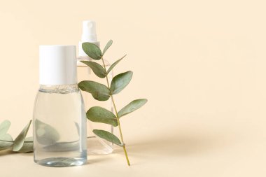 Su şişeleri ve bej arka planda yeşil dallar, yakın plan.