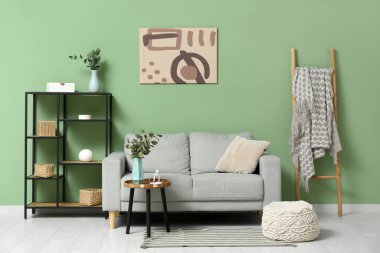 Oturma odasının içinde okaliptüs dalları olan kanepe, masa ve vazo.