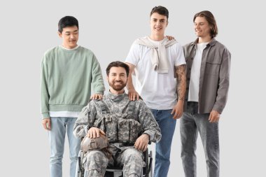 Tekerlekli sandalyedeki bir grup genç adam ve asker arka planda