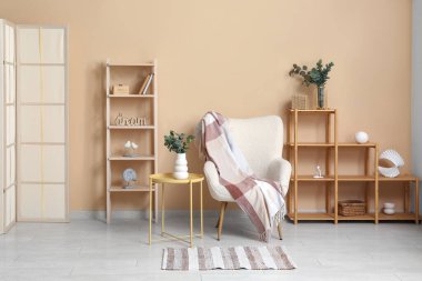 Koltuk, raf üniteleri ve okaliptüs dallı vazolar odanın içinde.