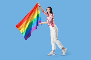 Beautiful young woman with LGBT flag on blue background
