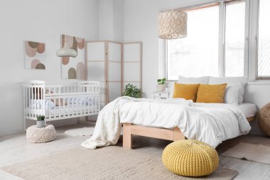 Büyük yataklı, bebek karyolası ve katlanabilir ekranlı bir ışık odası.